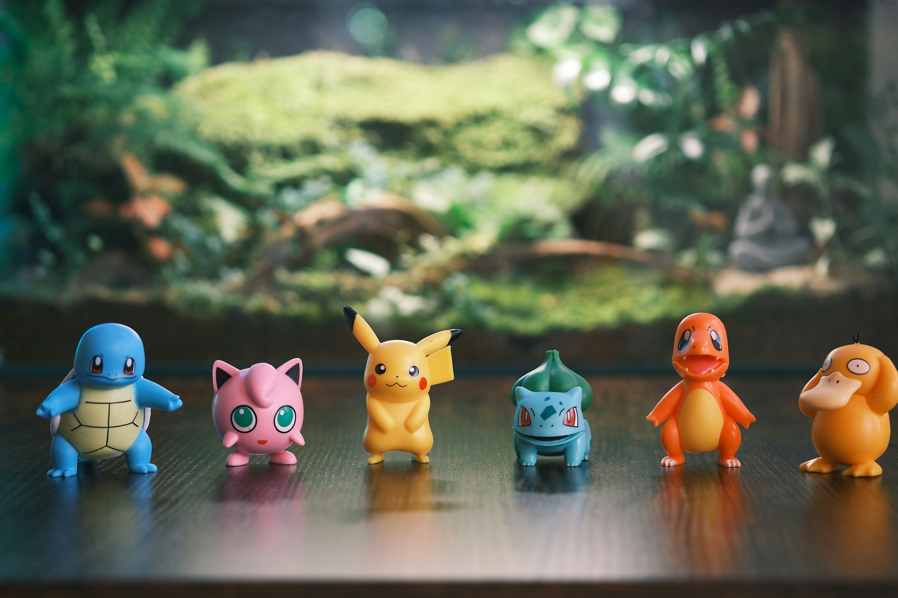 Six pokemon figurines lined up on a wooden surface.