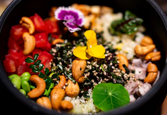 A colorful bowl of rice with cashews and vegetables.