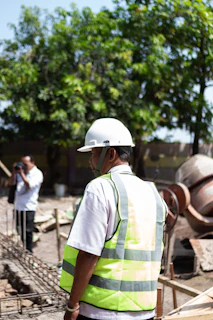 Construction worker wearing a hard hat and vest at site.