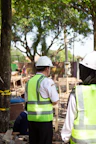 Workers in hard hats and safety vests at construction site.