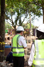 Workers in hard hats and safety vests at construction site.