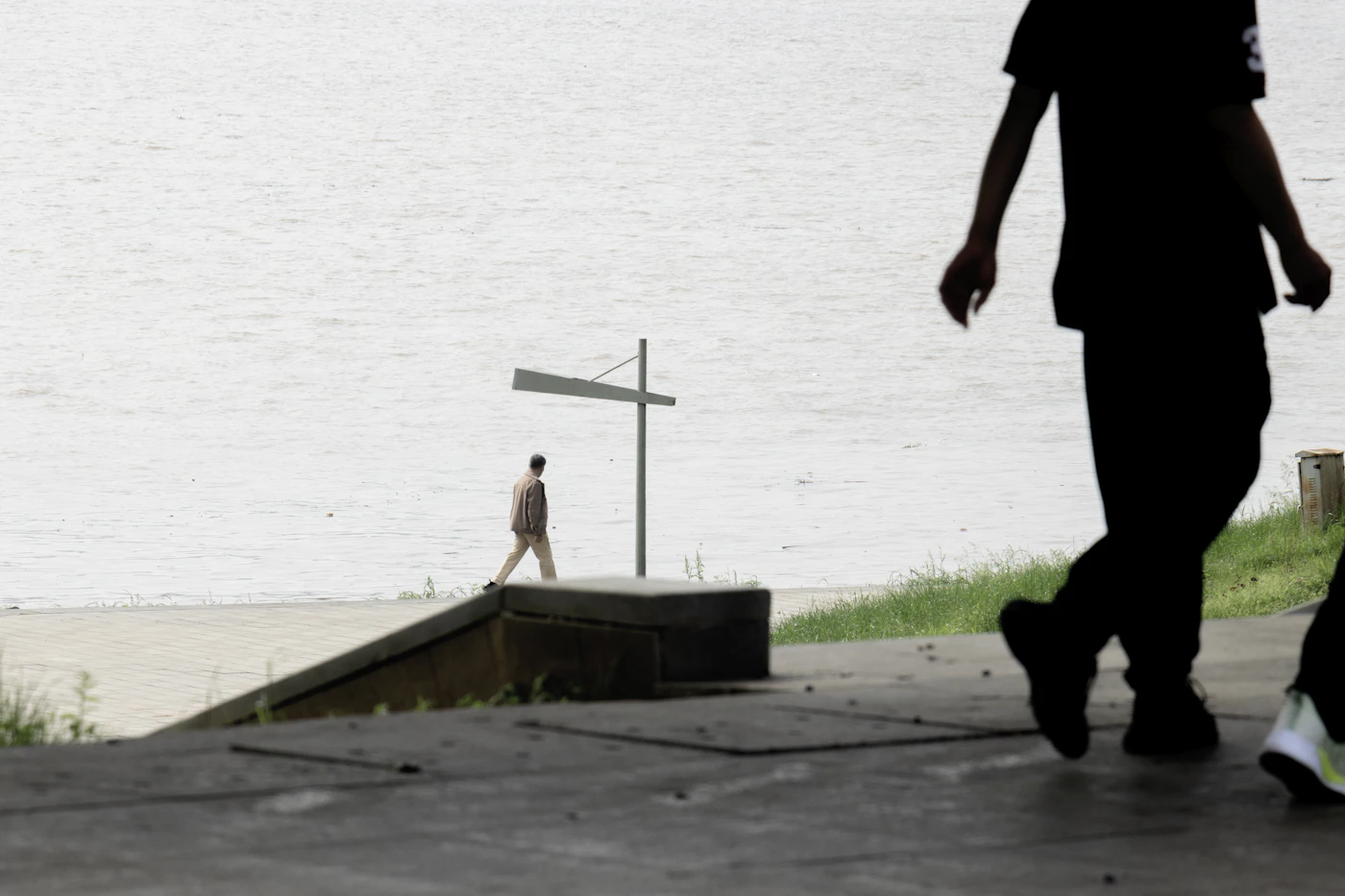 Menschen auf einem ruhigen Weg am Wasser als Symbol für bewusstes Weitergehen