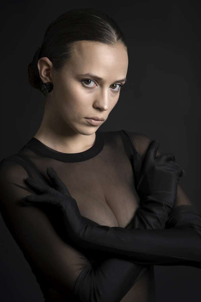 Model in a sheer black mesh top against a dark backdrop
