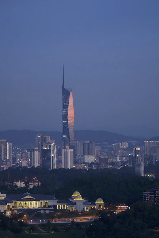 Modern city skyline with illuminated skyscrapers at dusk.