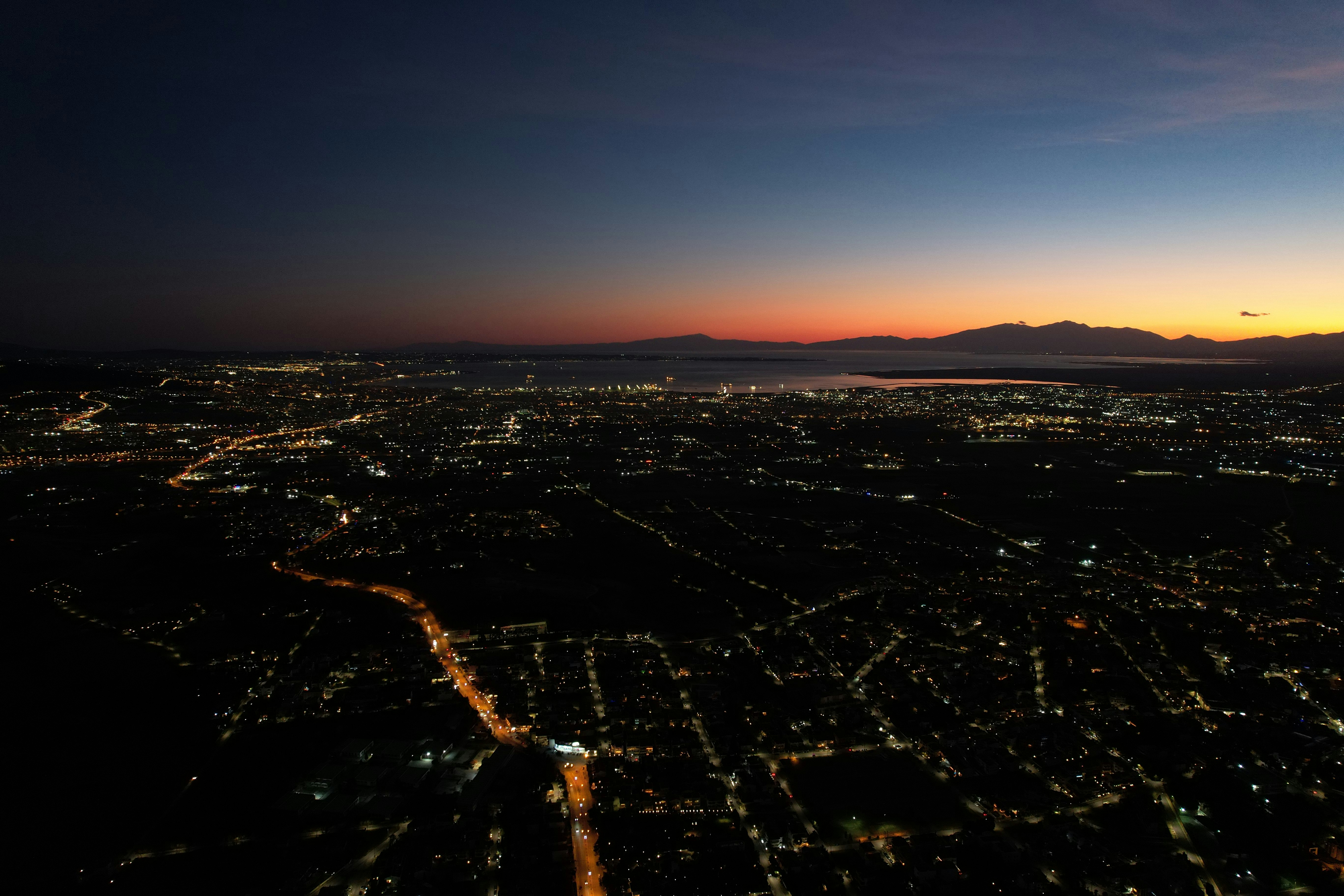 Aerial view of a city at dusk with glowing lights.