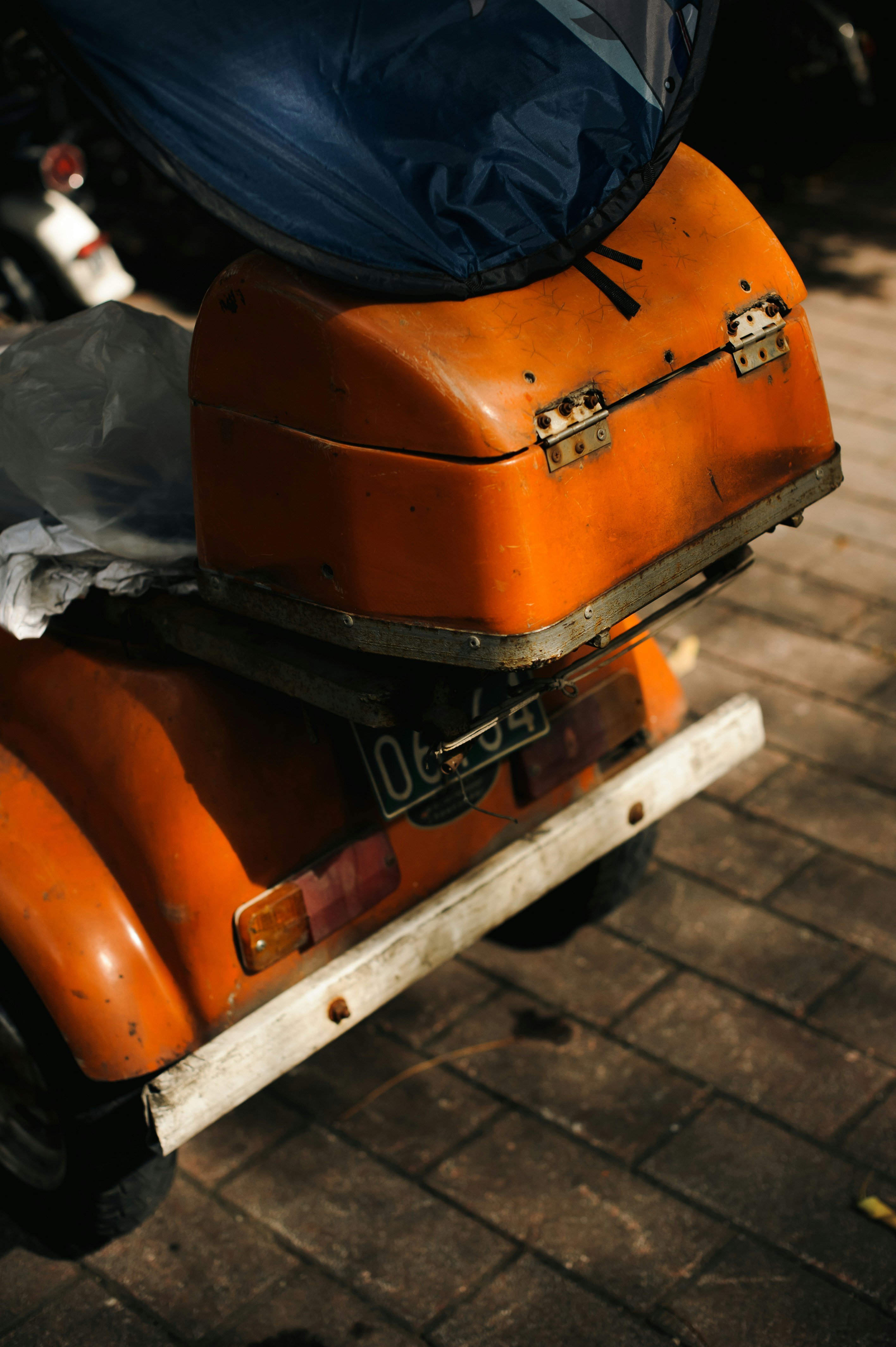 An old orange scooter with a blue cover