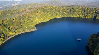 Calm blue lake surrounded by autumn forest and hills.