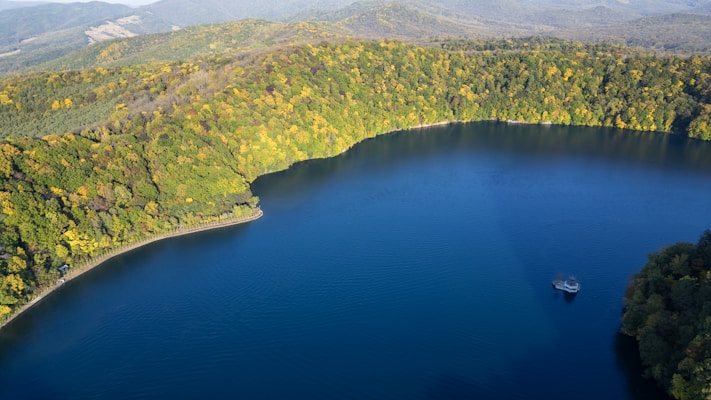 Calm blue lake surrounded by autumn forest and hills.