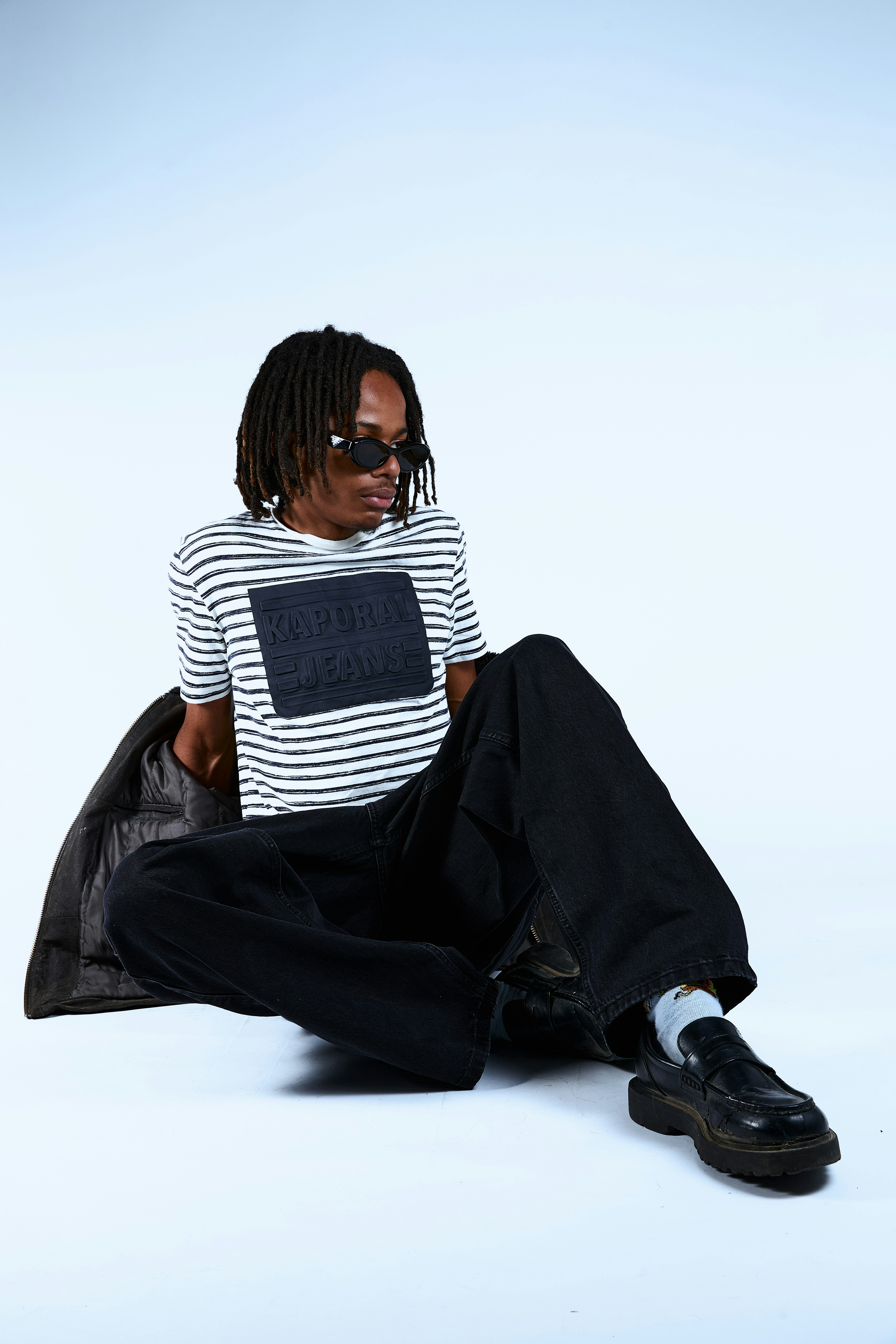 A person with dreadlocks wearing sunglasses and striped shirt.
