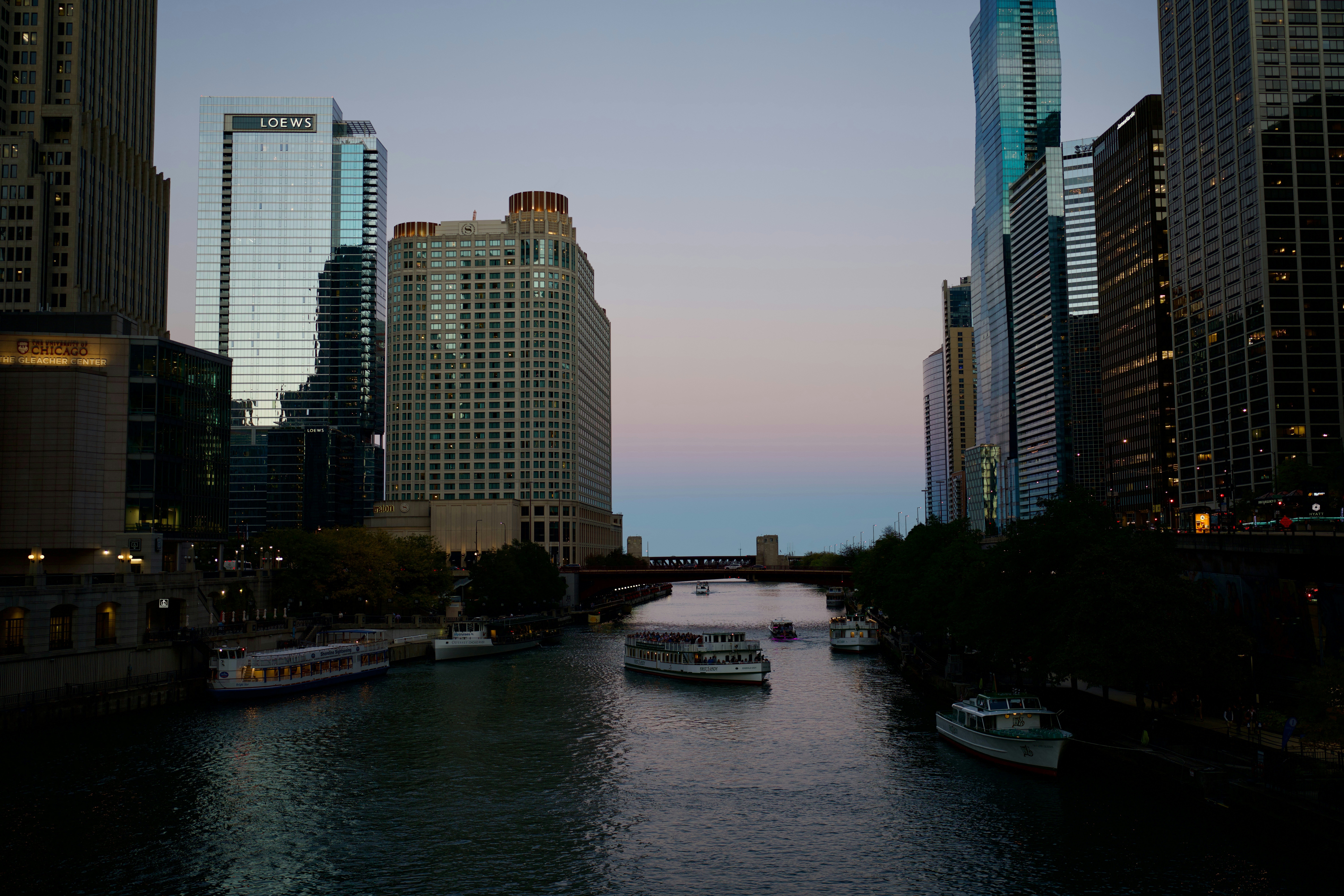 The Chicago Riverwalk at sunset with city lights reflecting on the water - chicago river north things to do