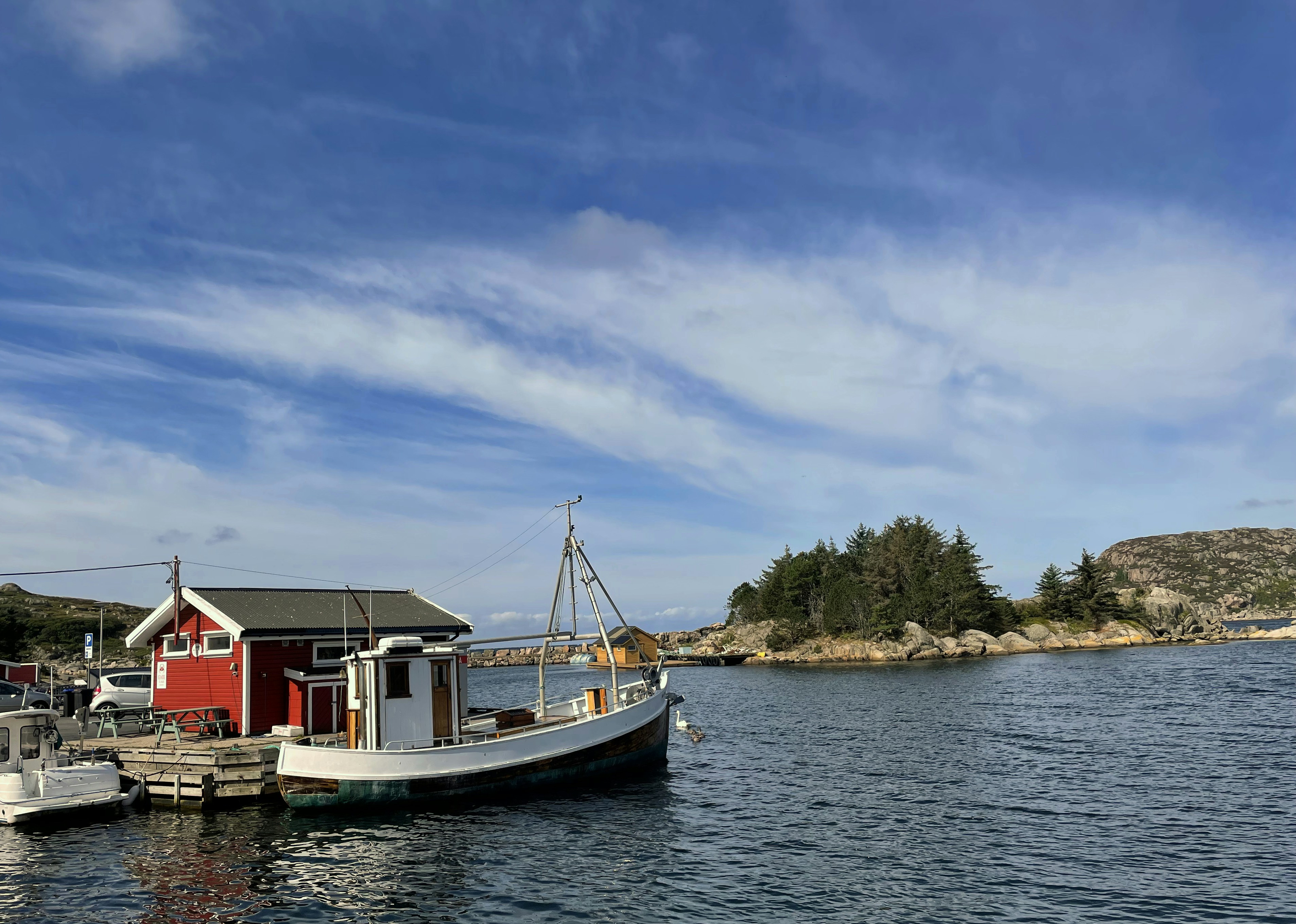 Boat docked by a red building near islands.