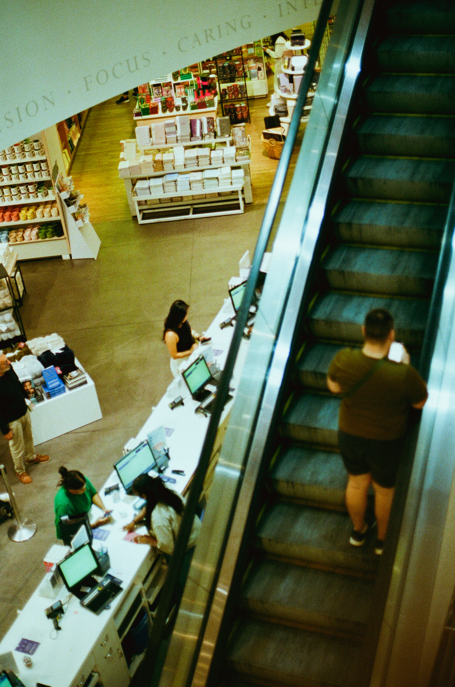 People on escalator in a brightly lit store.