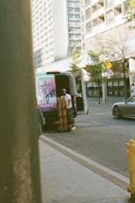 Man unloading boxes from a van on a city street.