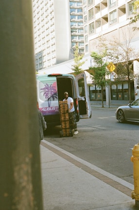 Man unloading boxes from a van on a city street.