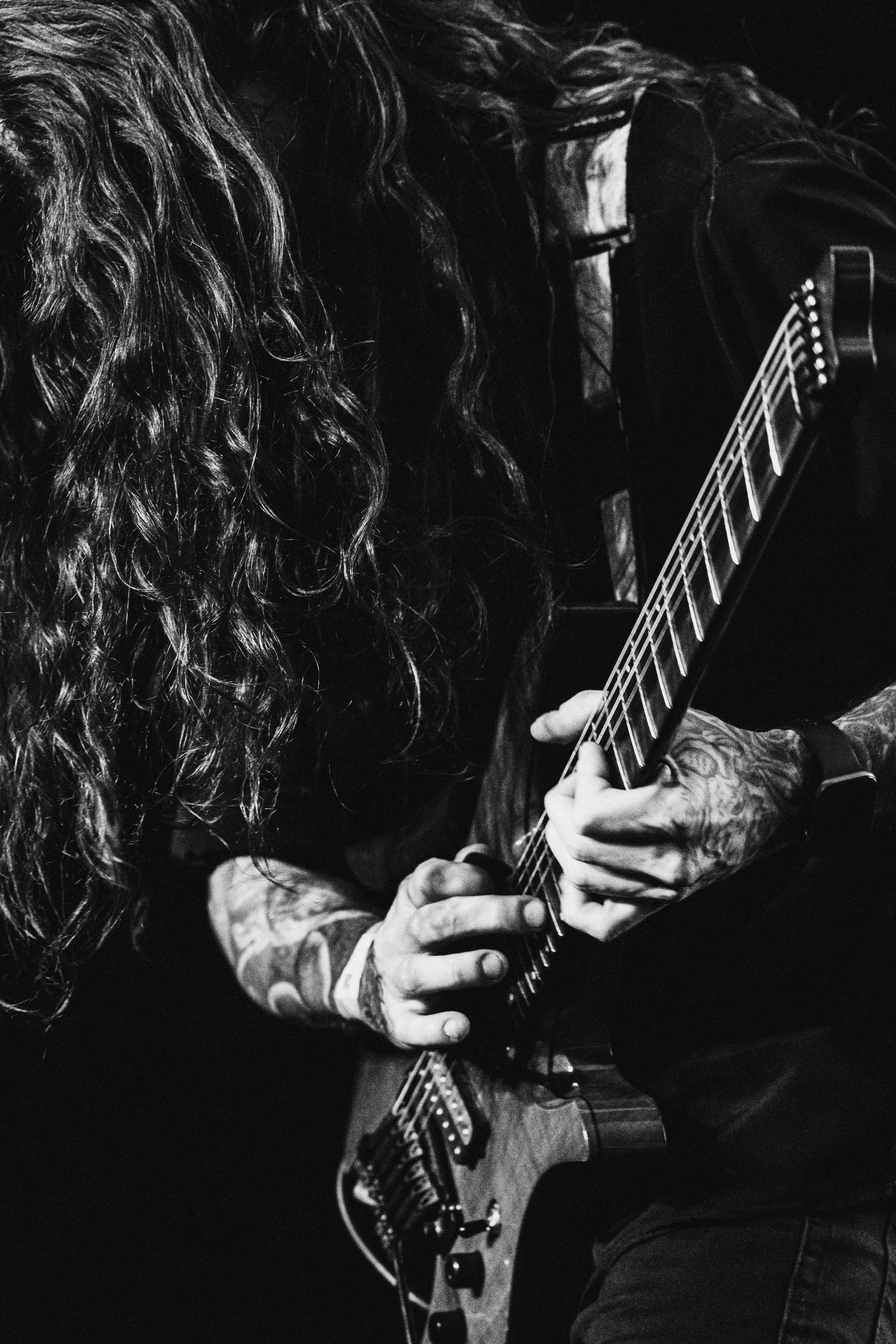 Músico con cabello largo tocando guitarra en concierto de metal
