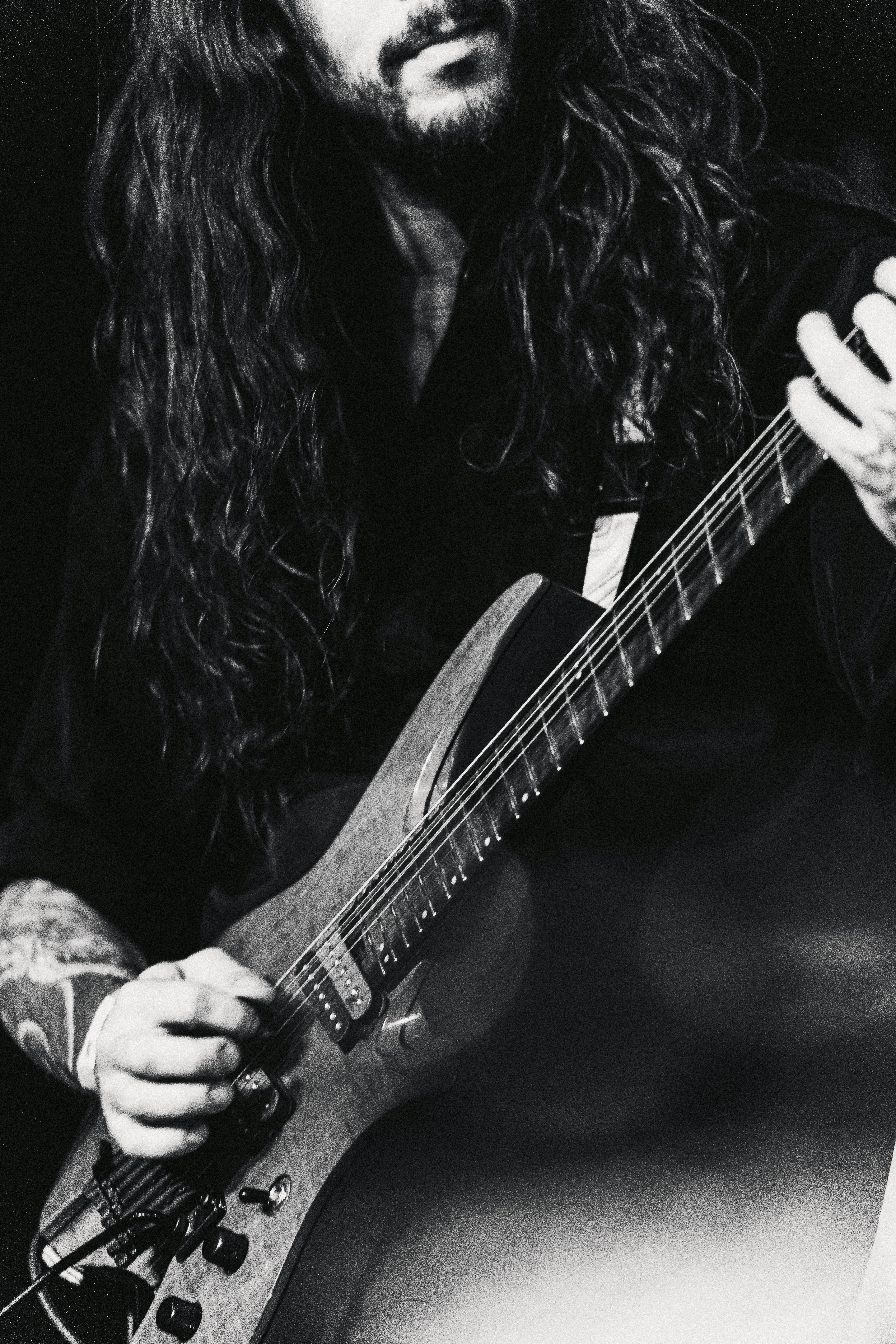 Hombre con cabello largo tocando una guitarra eléctrica.