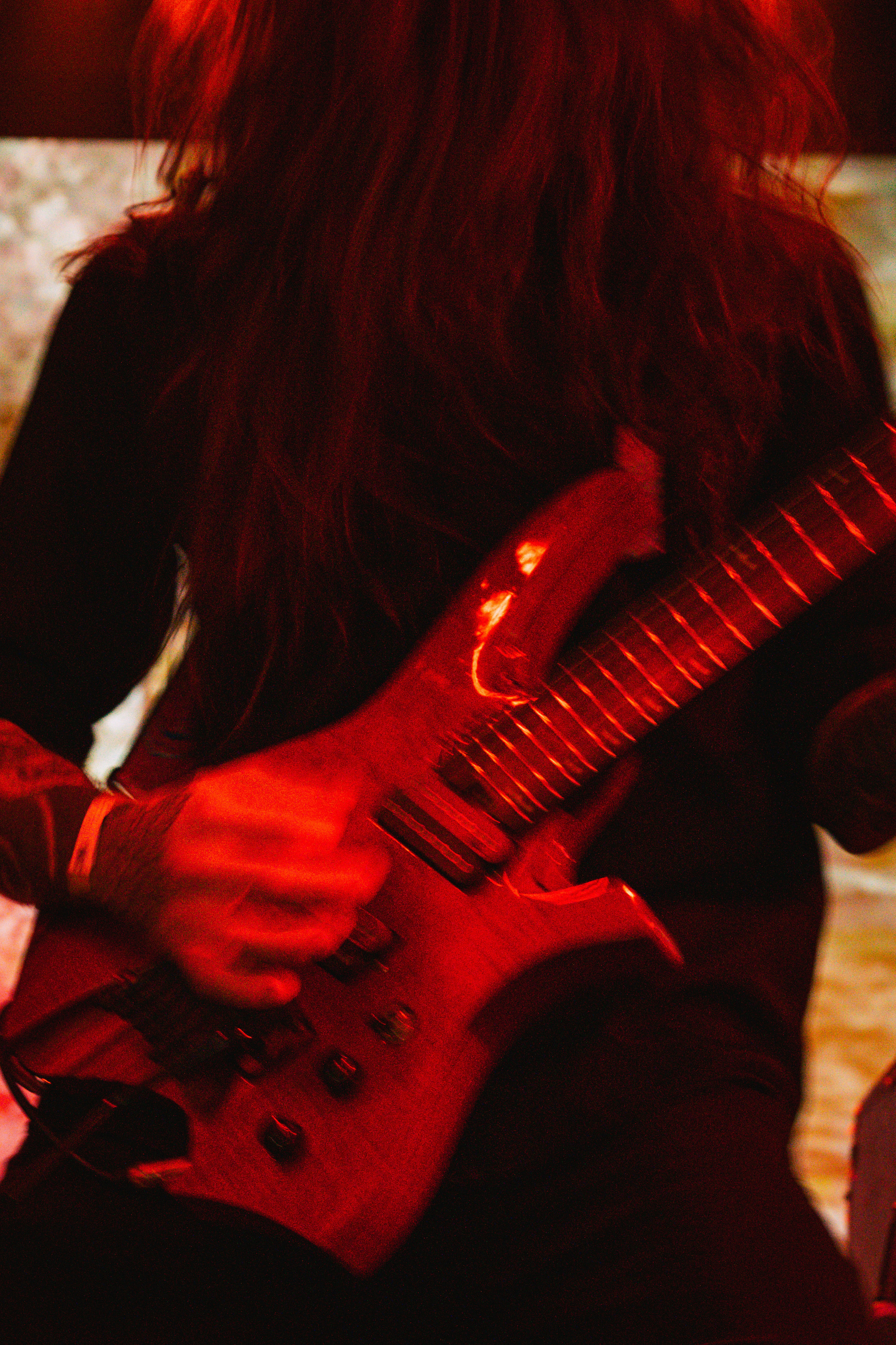 Person playing electric guitar under red light