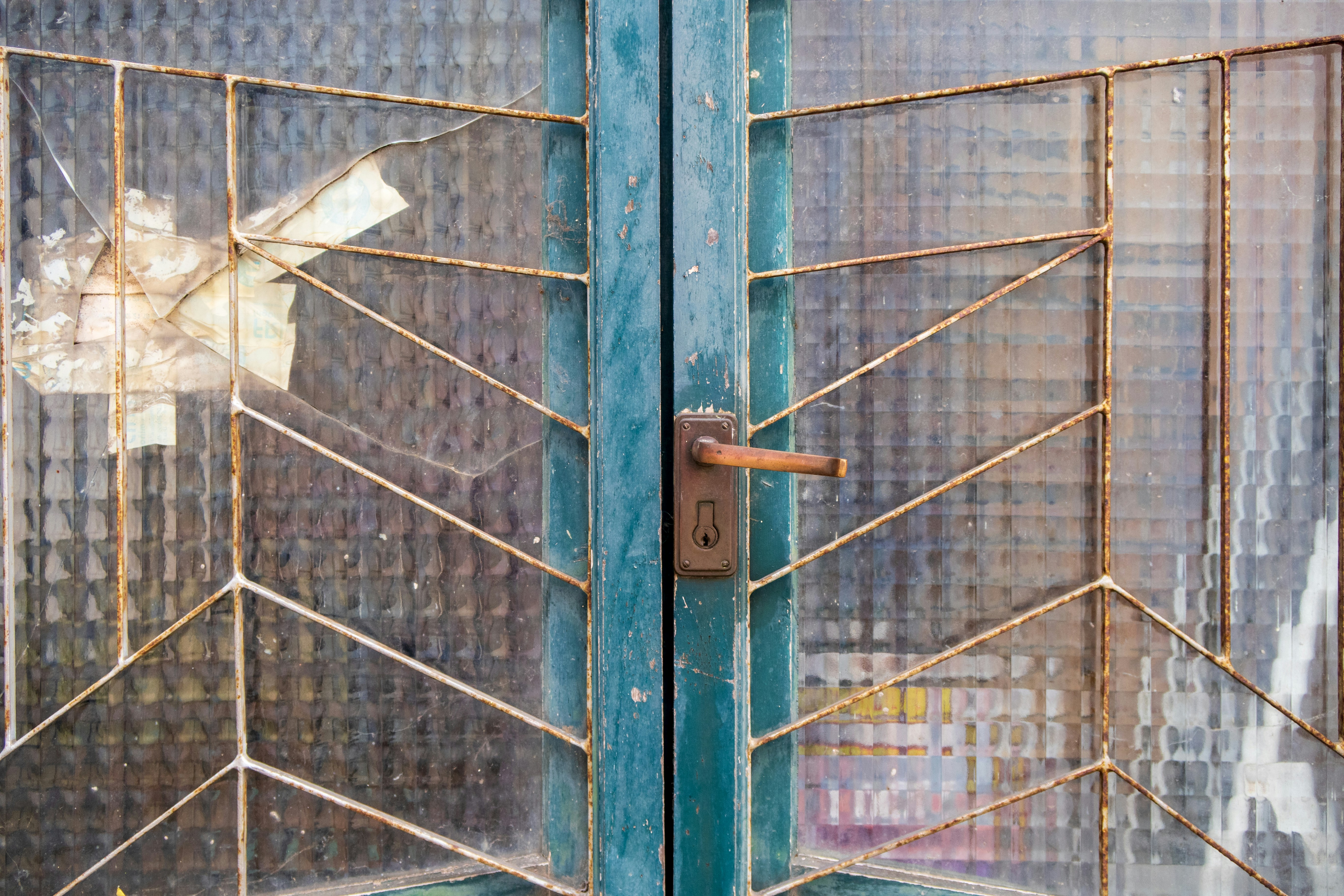 Primer plano de una puerta de metal desgastado con paneles de vidrio