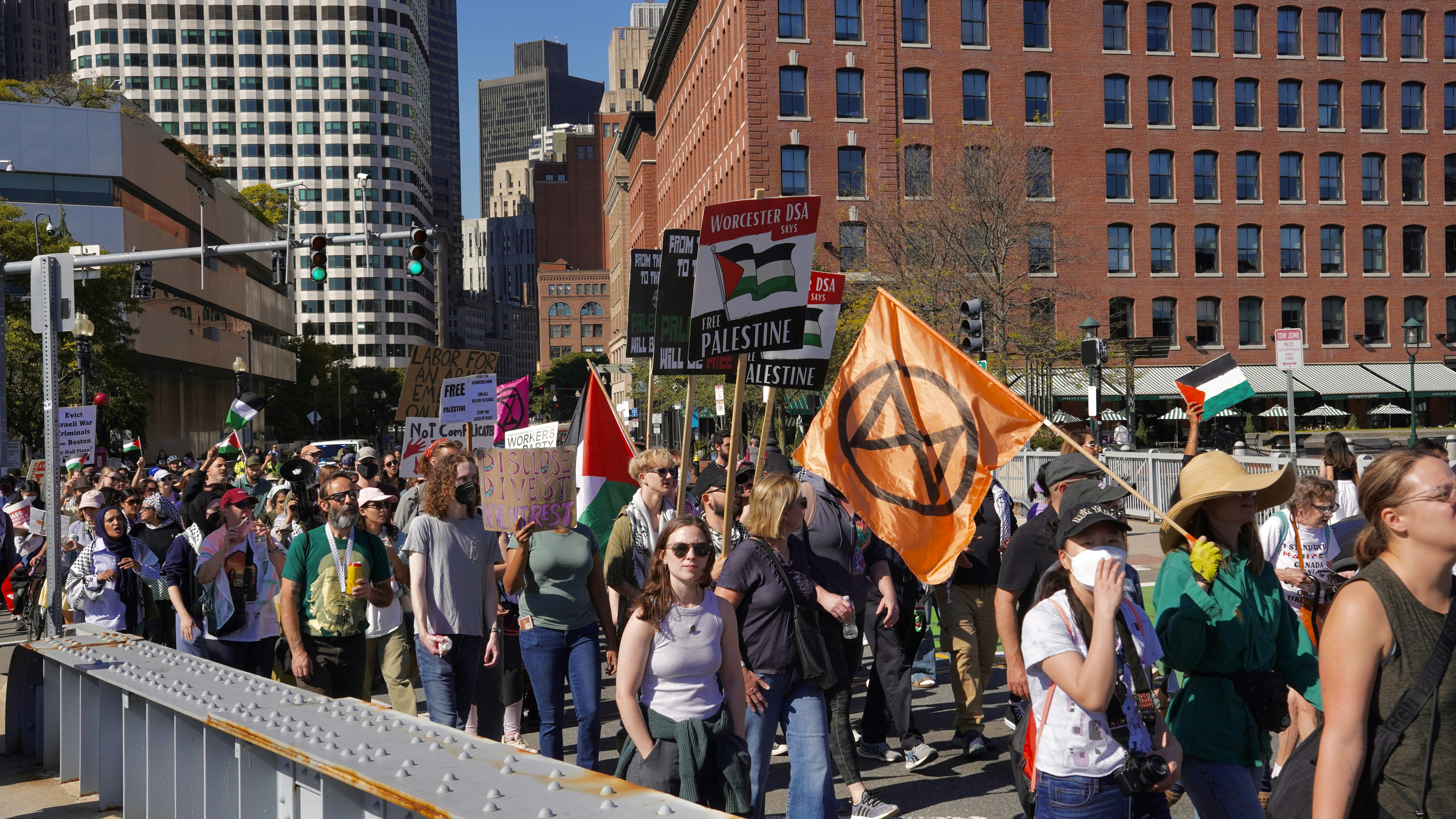 Protestors march with flags and signs in a city.