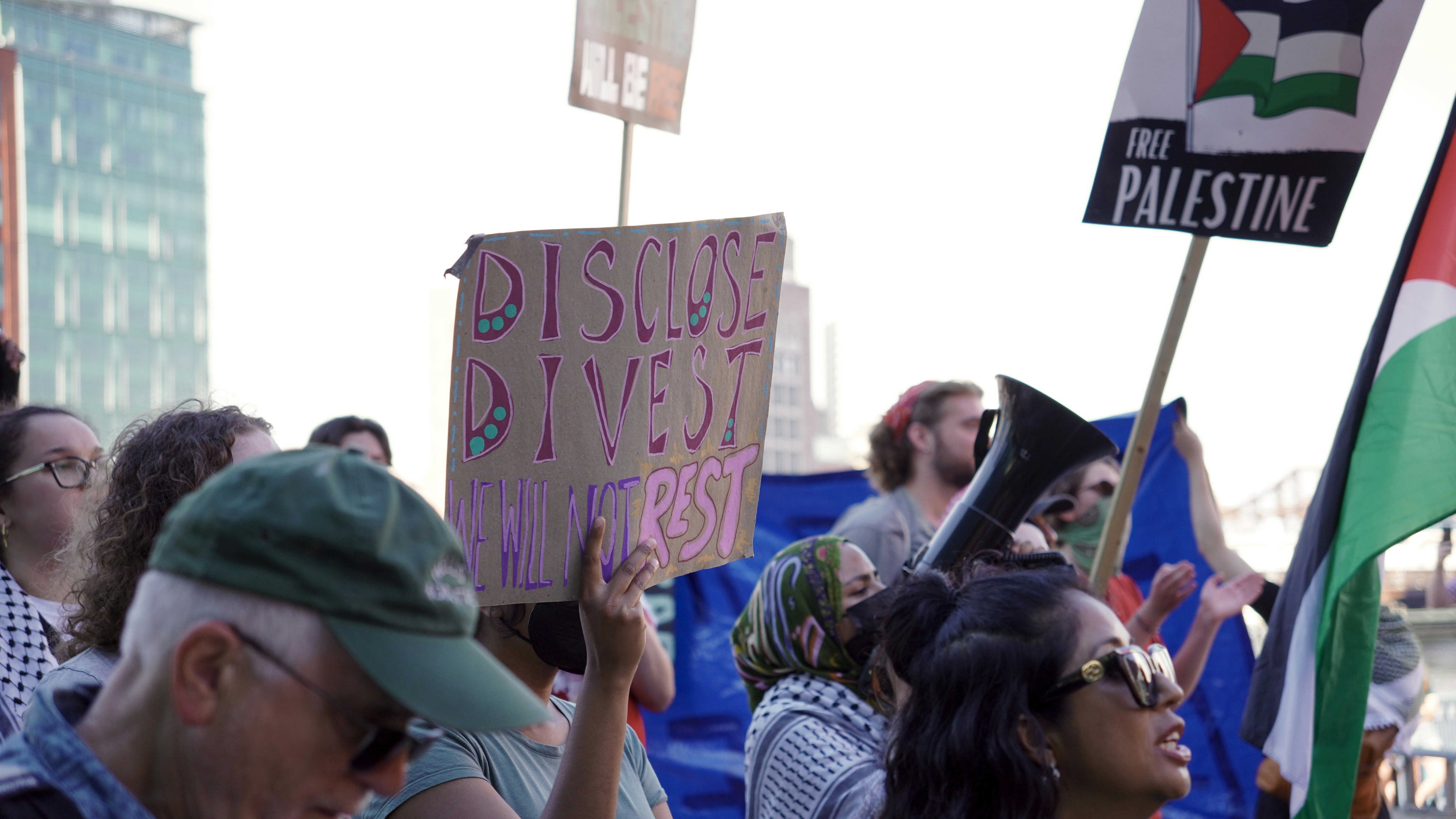 Protesters hold signs and flags at a rally.