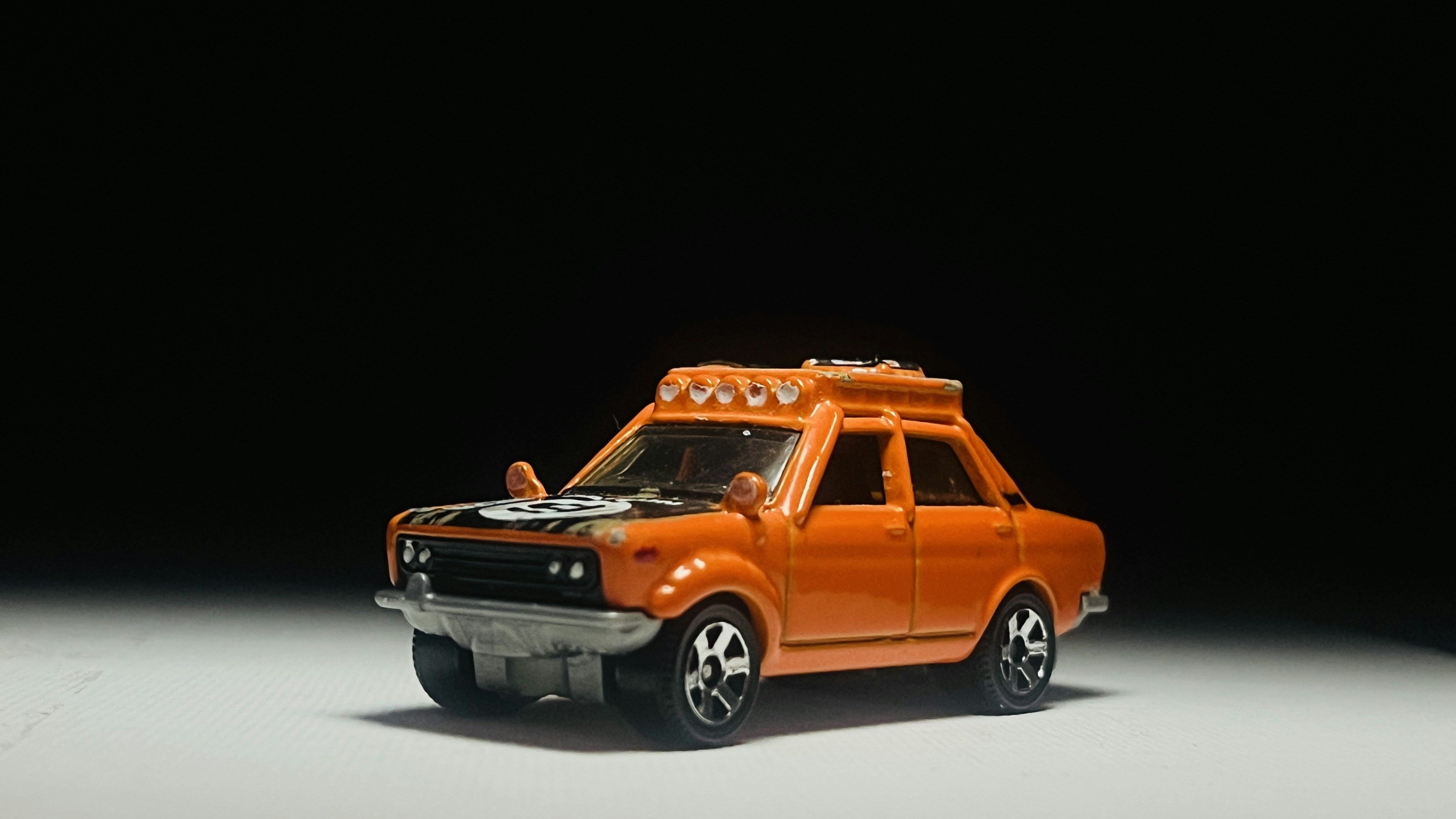 Orange toy car with roof rack on white surface