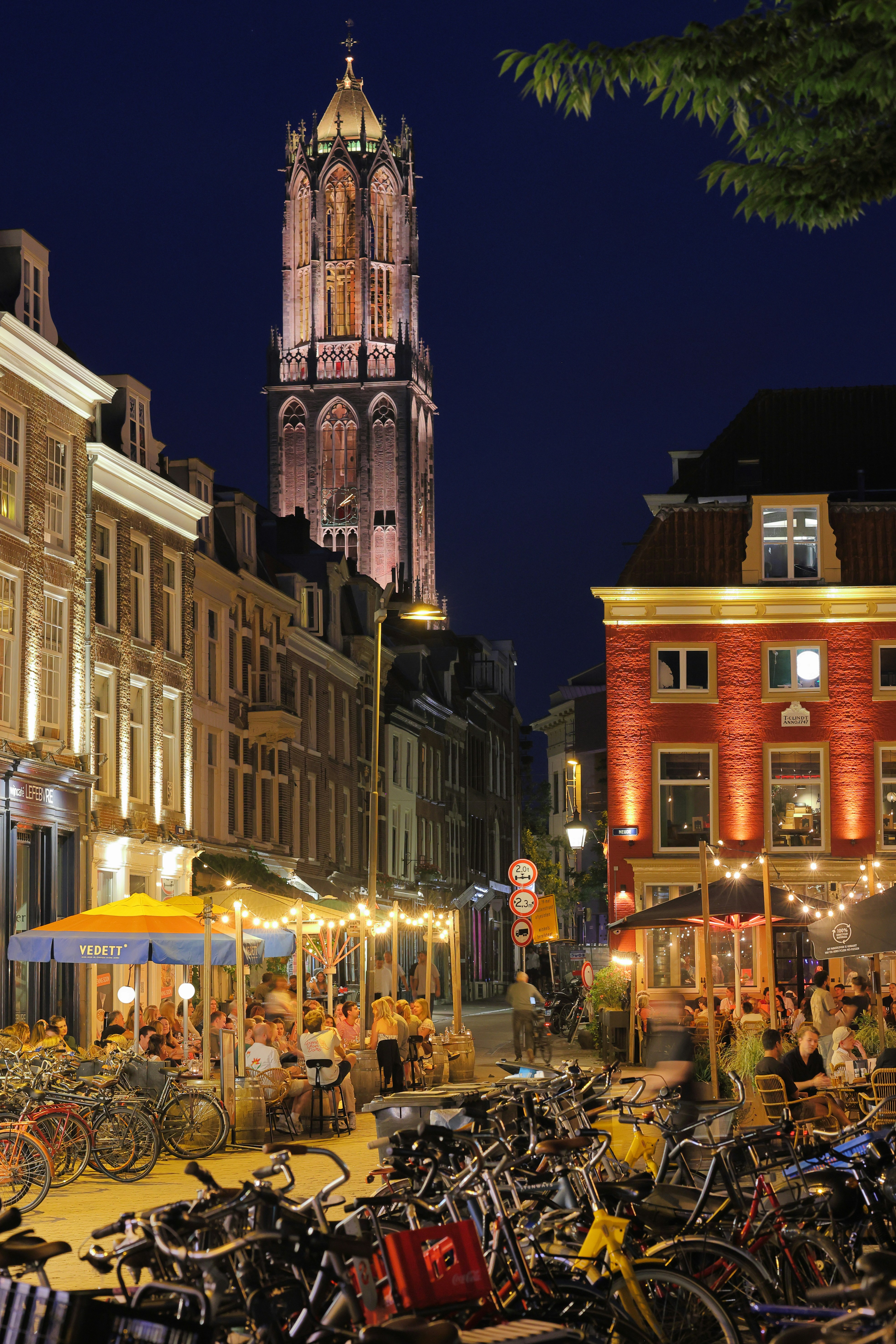 City street with outdoor dining and tall illuminated tower