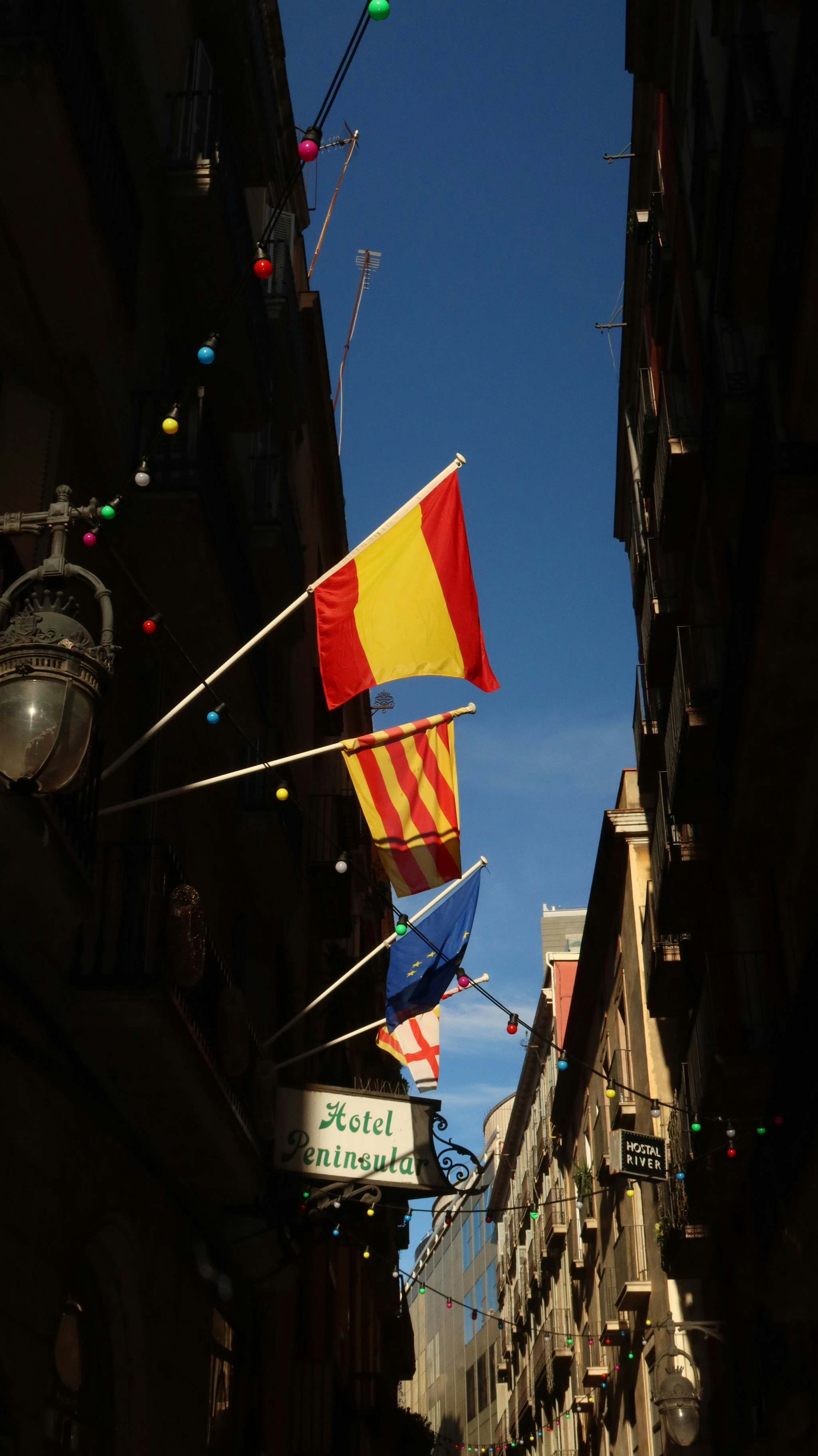 Flags flying between buildings on a sunny day.