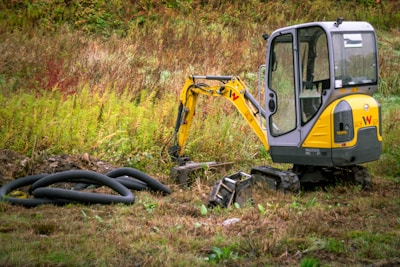 Mini excavator with coiled pipes on grassy ground