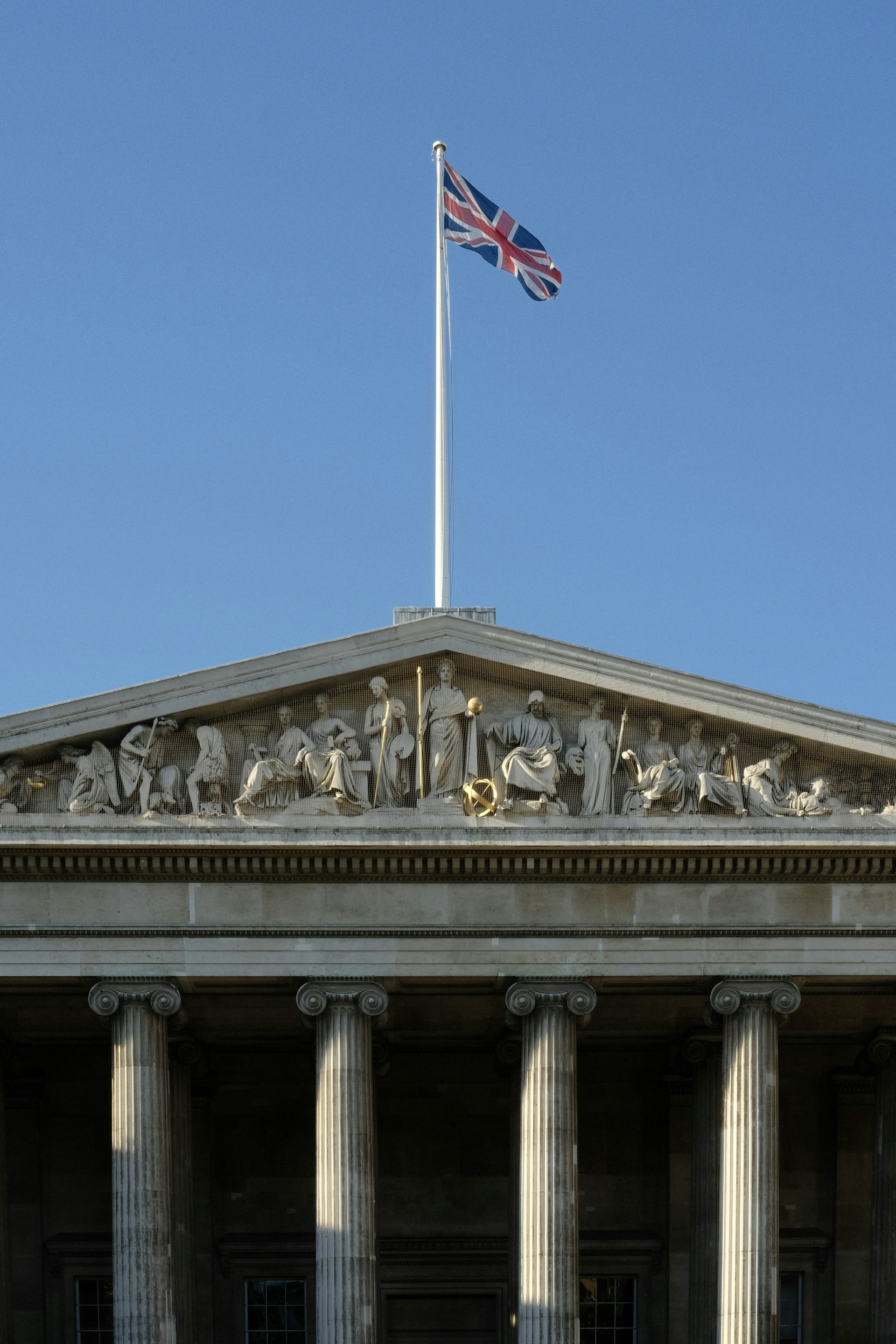 Union jack flag flying above classical building facade