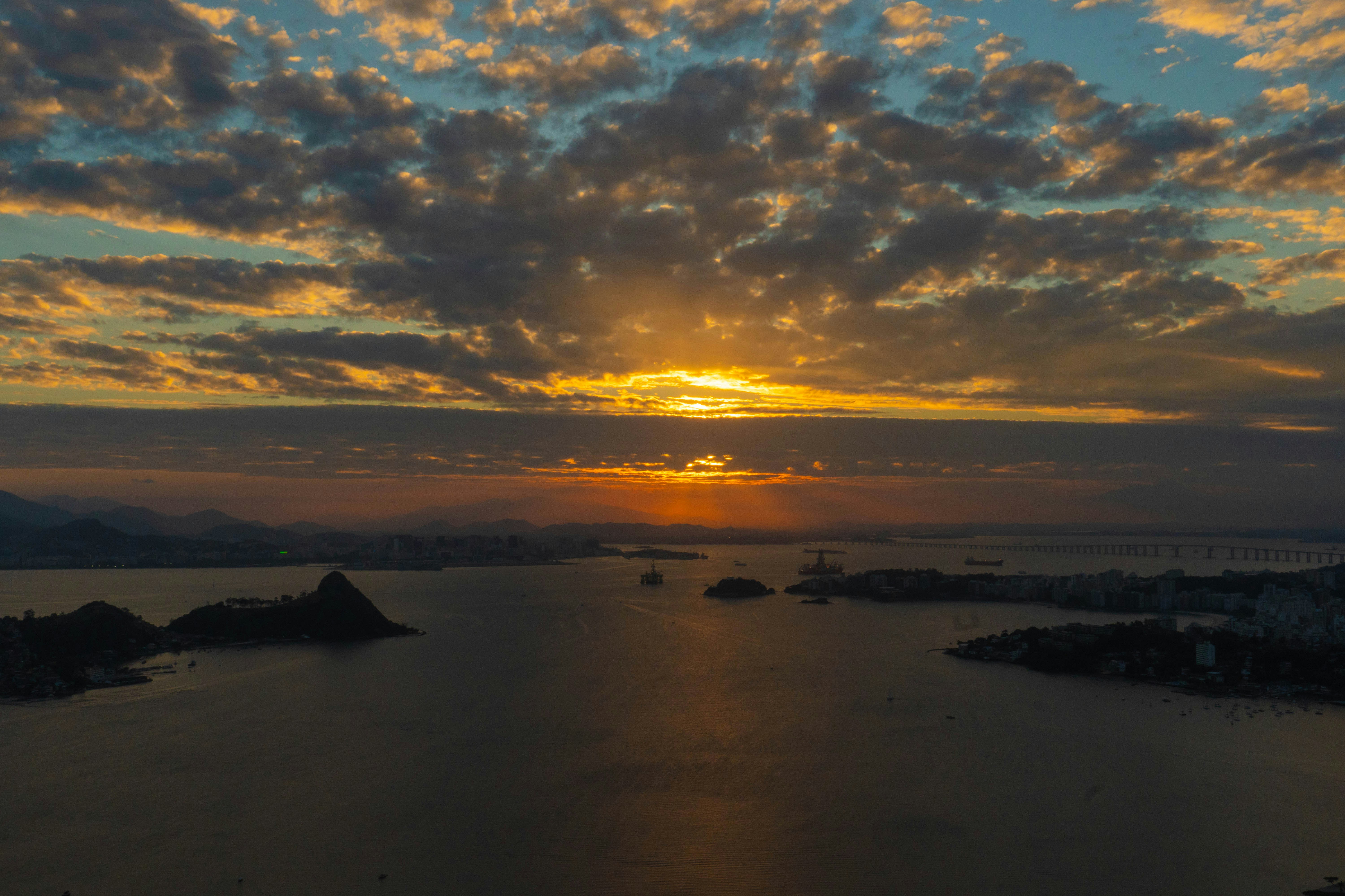 Sunset over a calm ocean with dramatic clouds.