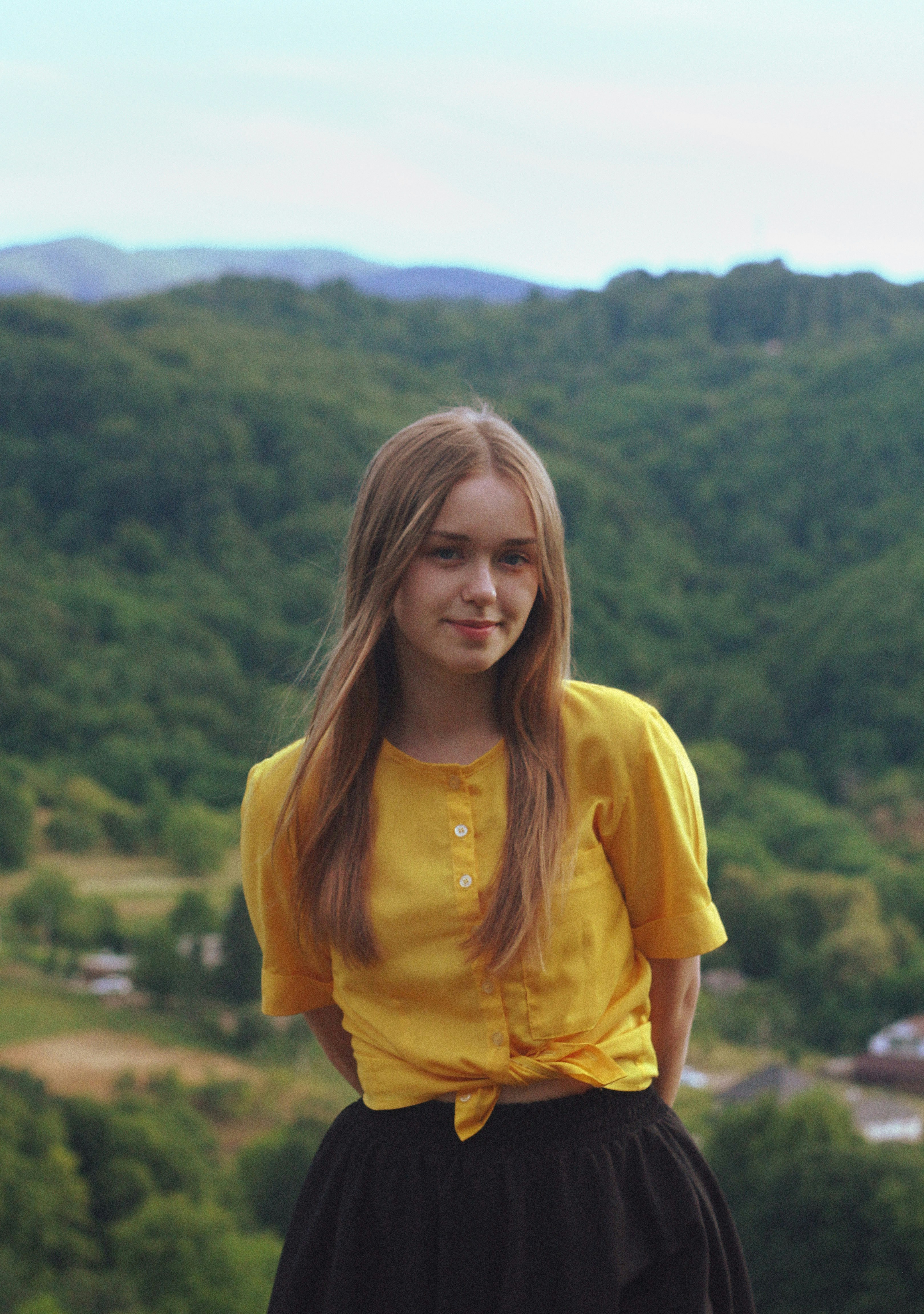 Young woman in yellow shirt with forested hills background