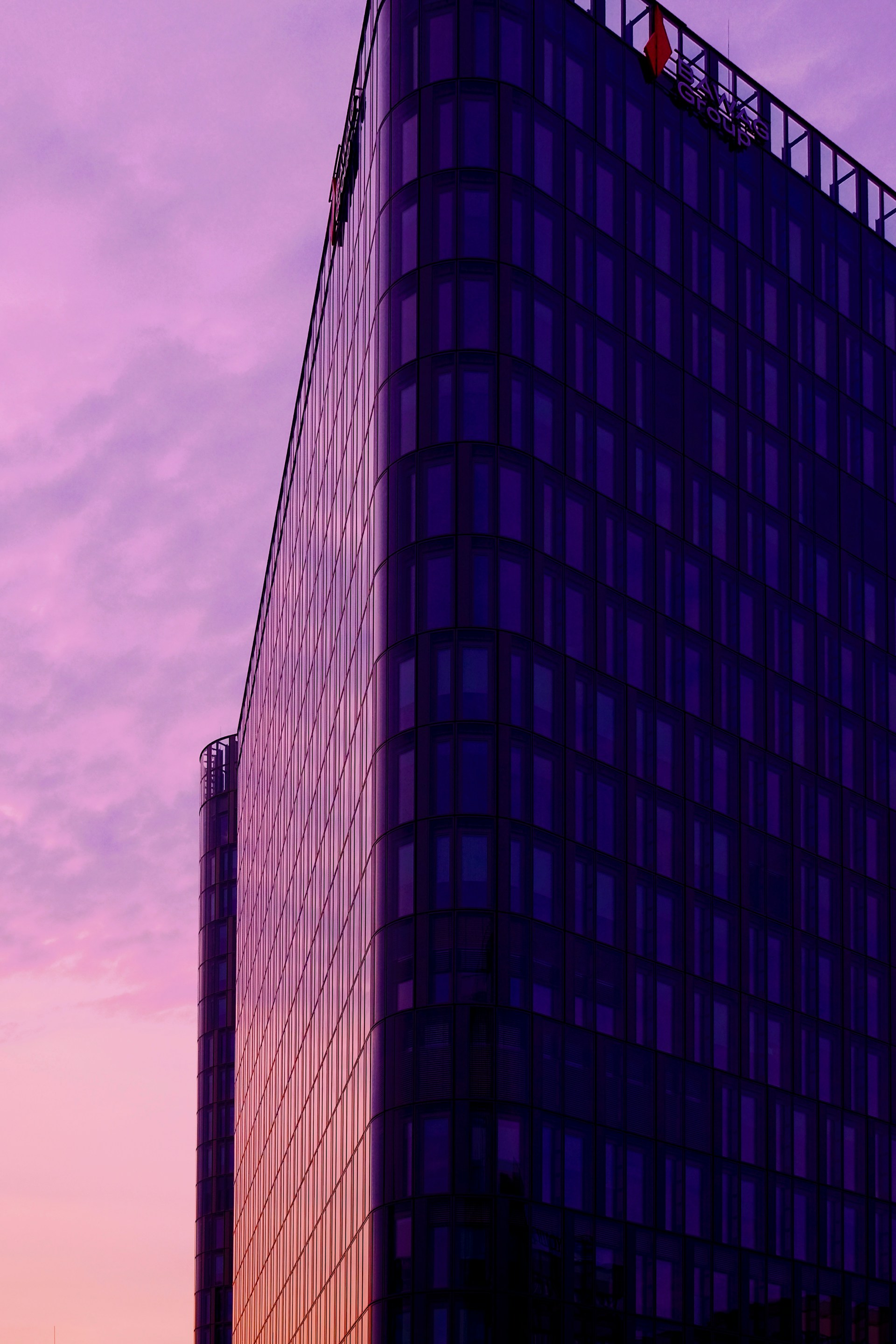 Modern skyscraper against a vibrant purple sunset sky