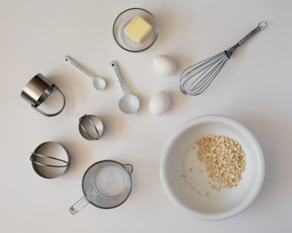 Baking ingredients and tools arranged on a white surface.