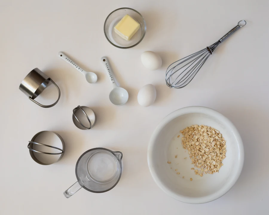 Measuring cups, spoons, a whisk and eggs on a white counter