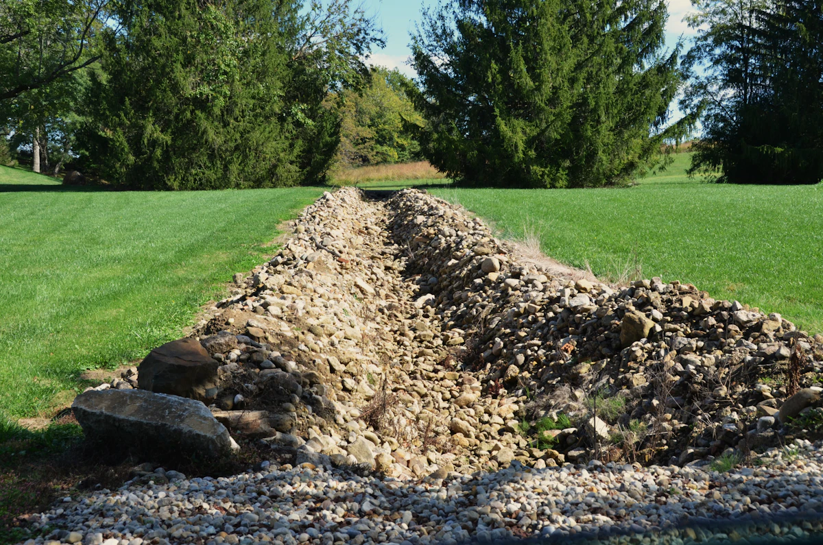 Drainage trench and gravel through a grassy yard for water management