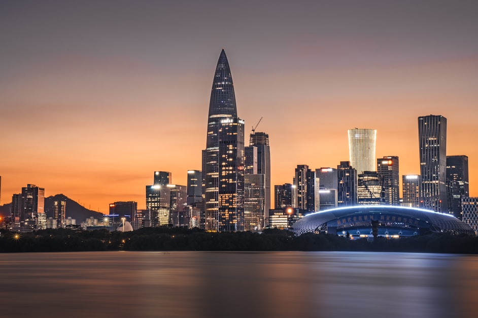 Shenzhen city skyline with skyscrapers lit up at sunset over the bay