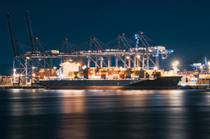 Cargo ship docked at a busy port at night.
