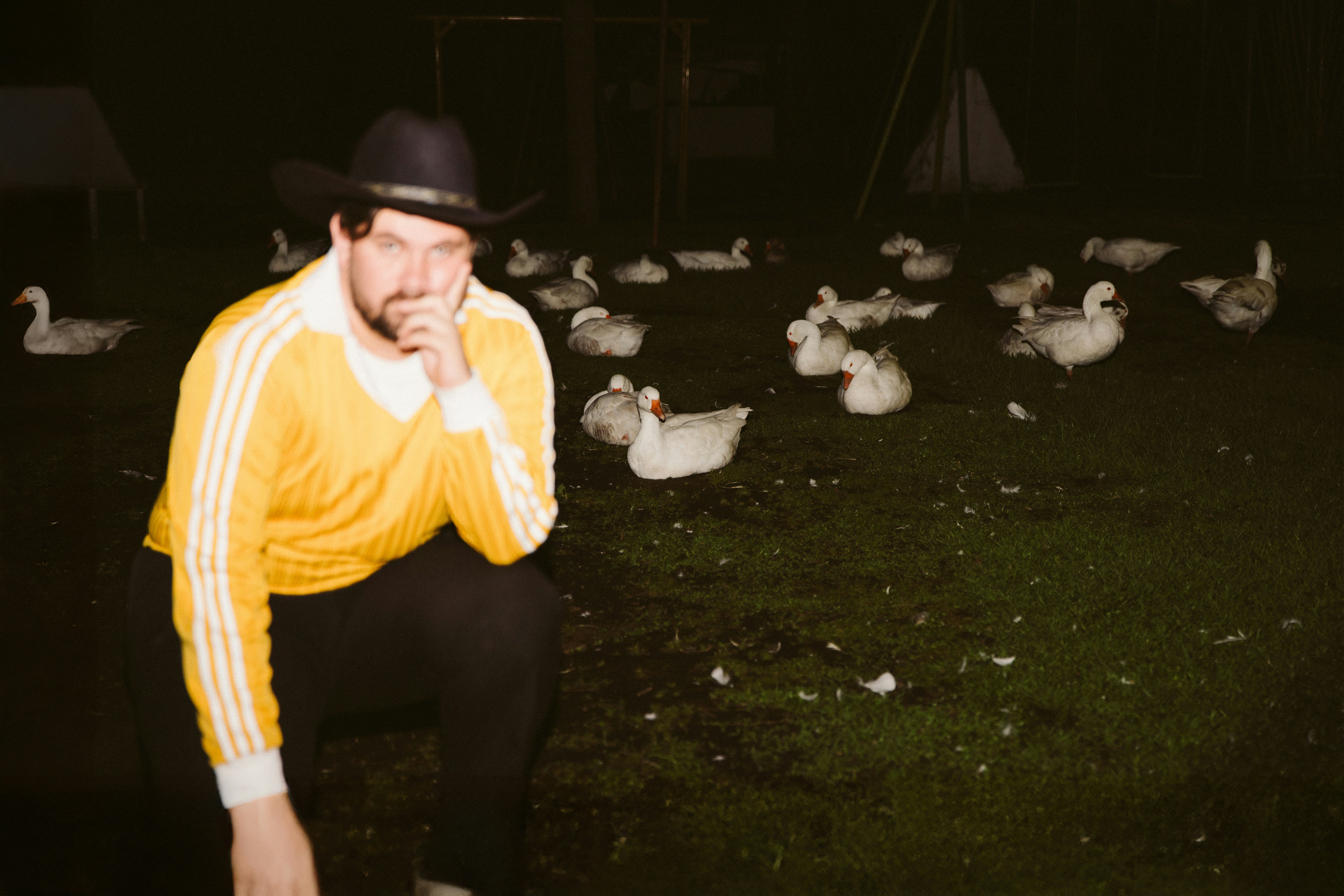 Mann mit Cowboyhut mit vielen Enten in der Nacht