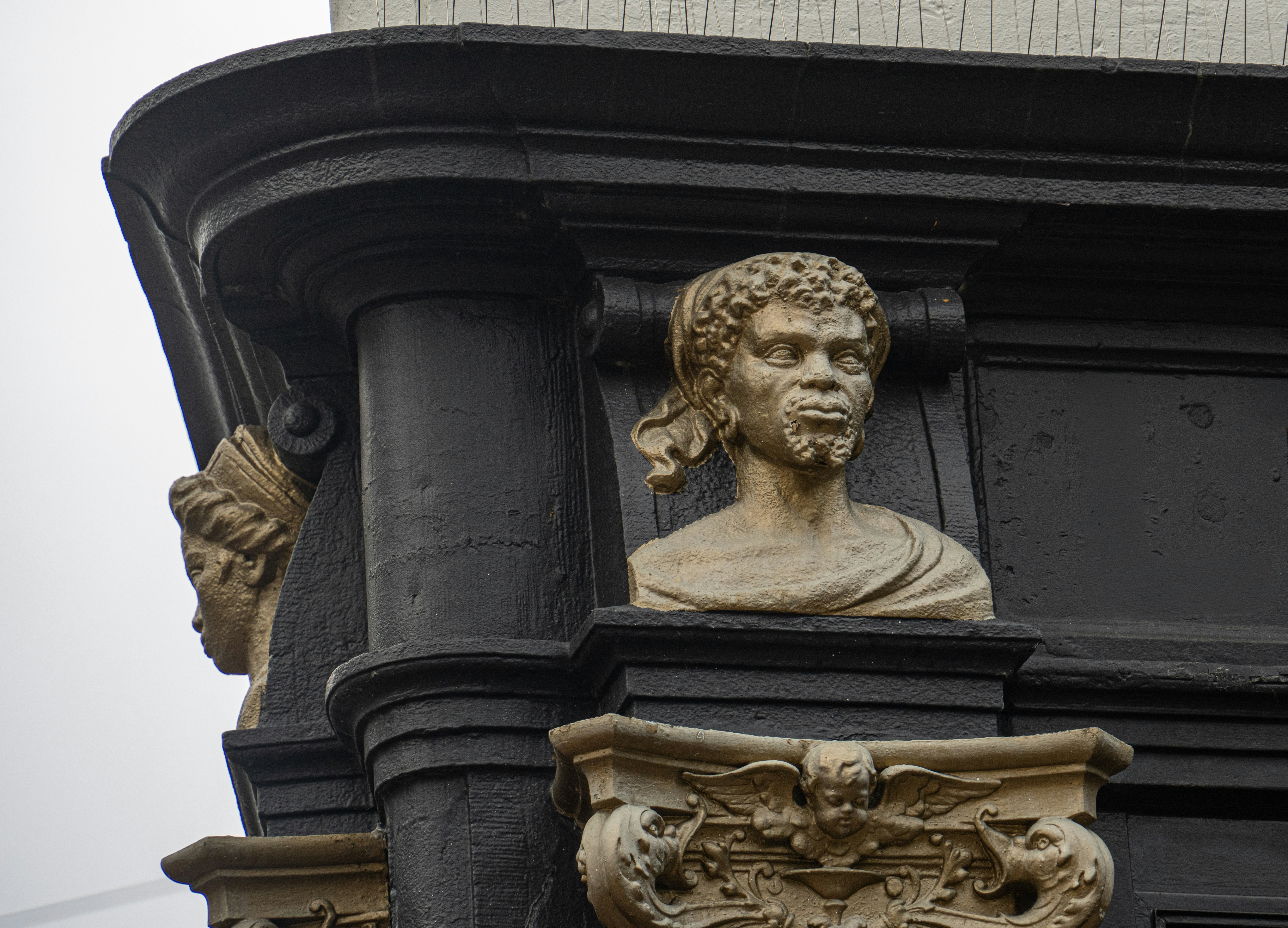 Busts of men on an ornate architectural structure.