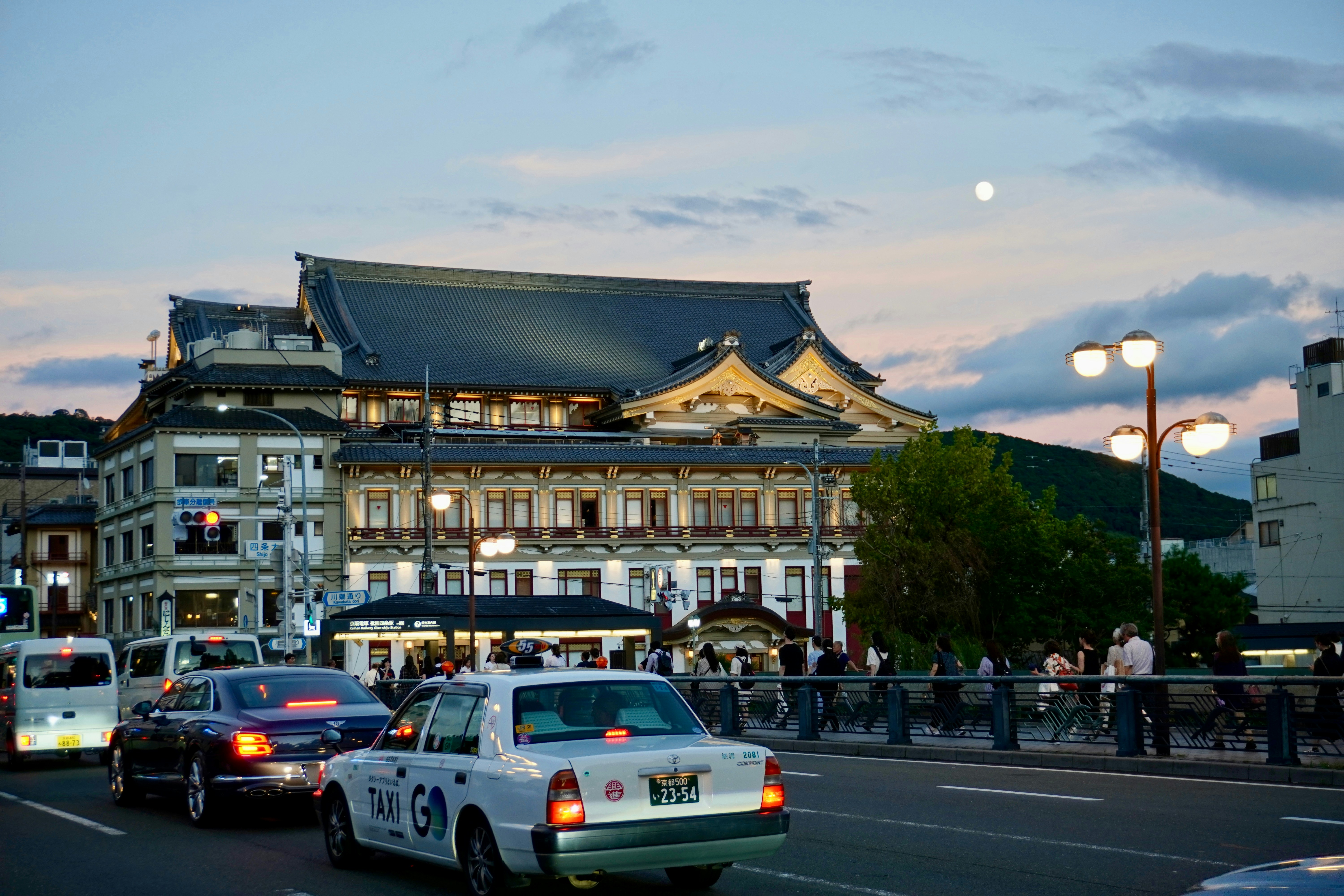 Cars on a street with traditional building at dusk.