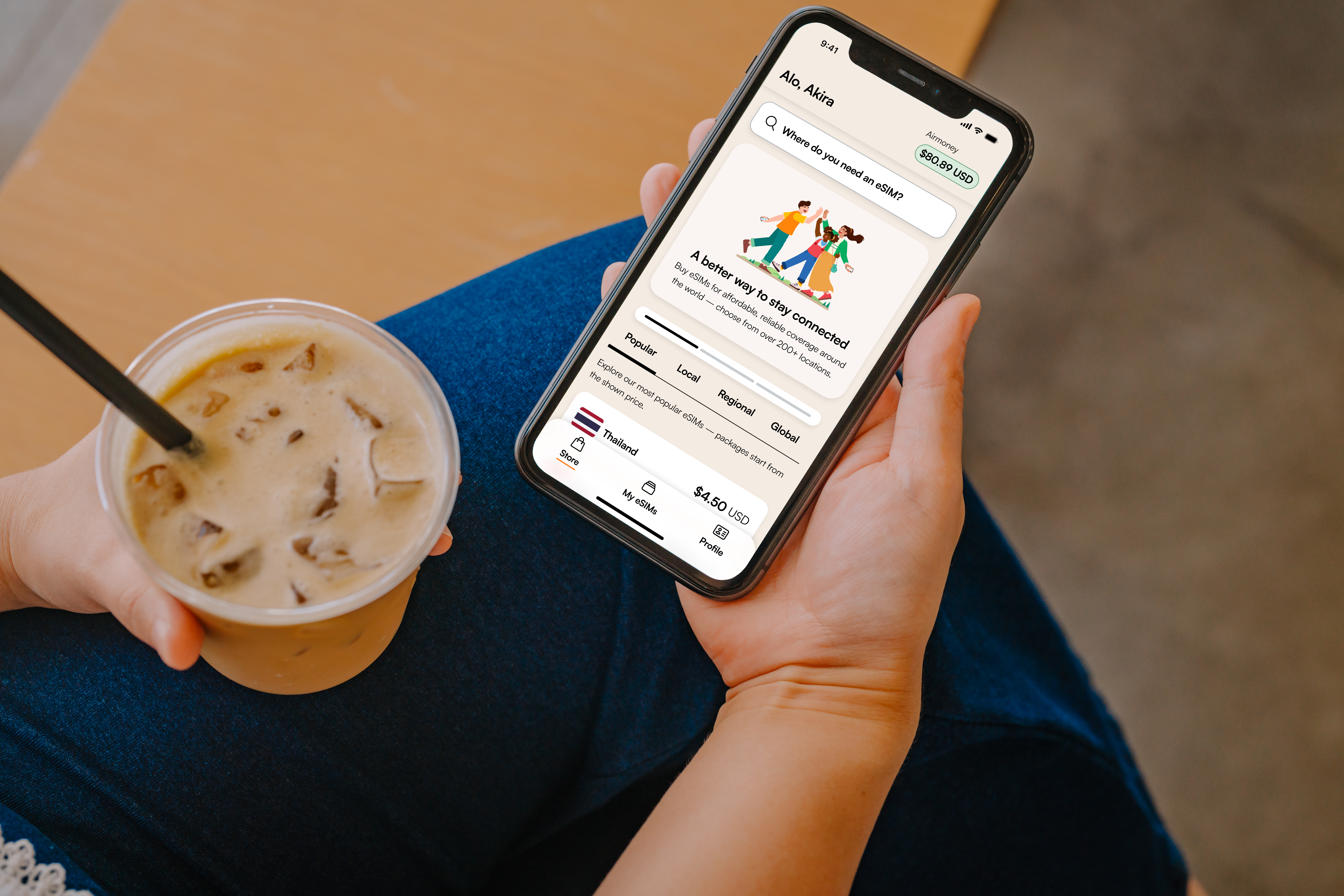 Person holding phone with app and iced coffee