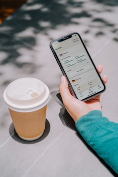 Person holding phone with coffee cup nearby