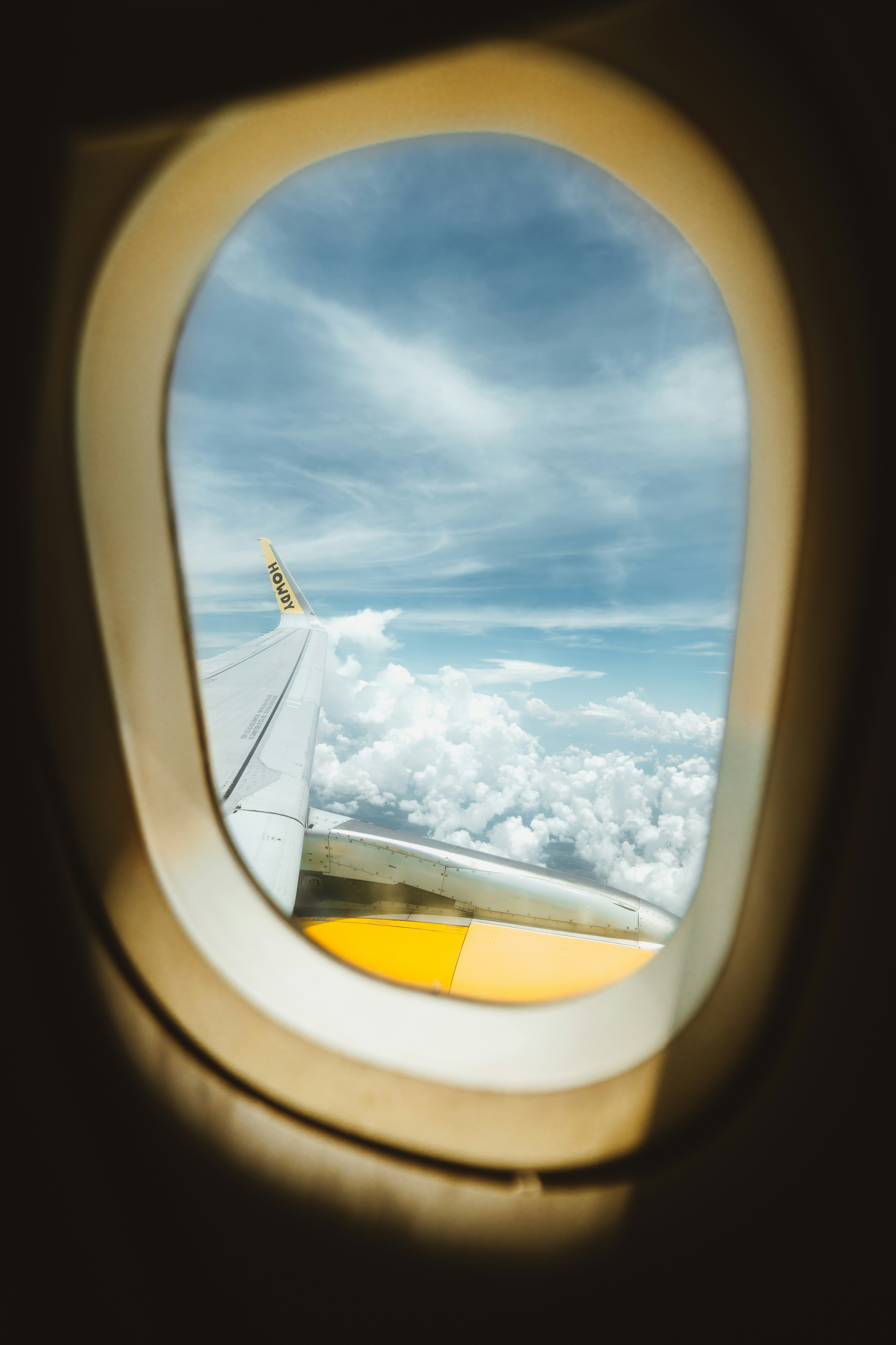 View of clouds and airplane wing through window