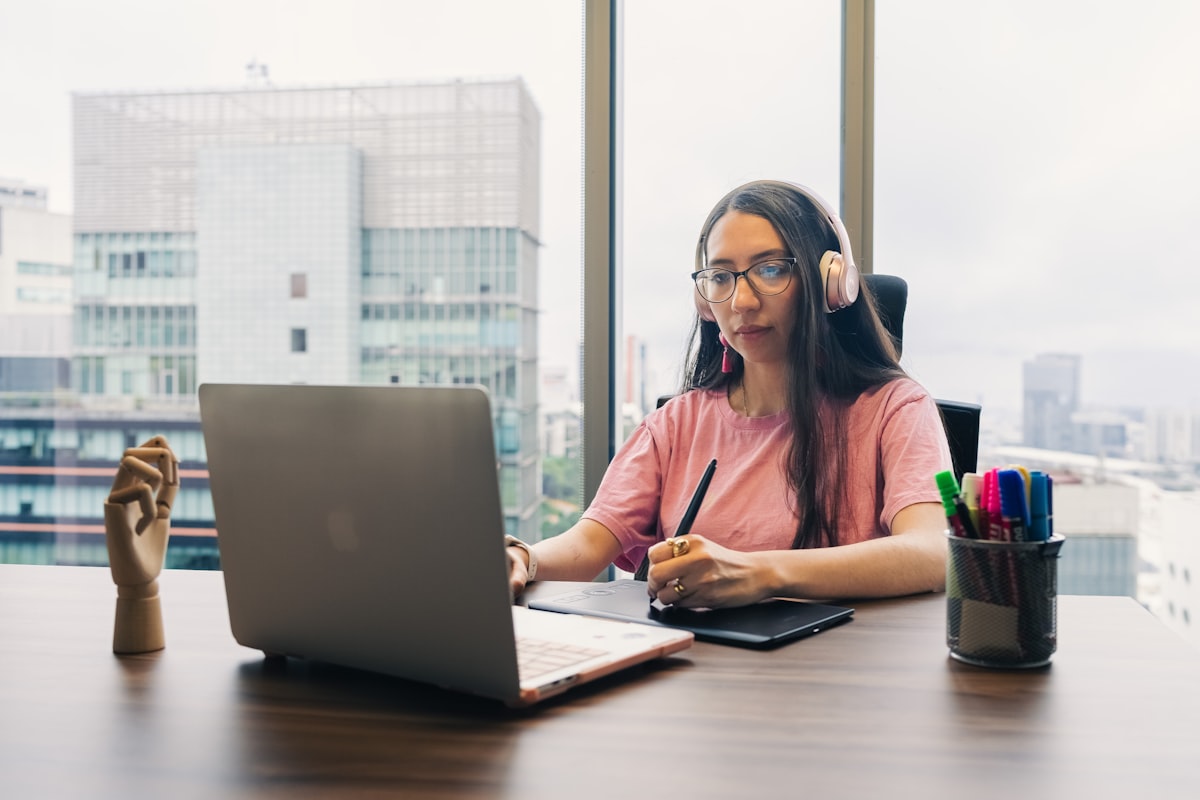 skillshare review 2026, woman working on laptop with stylus in creative workspace