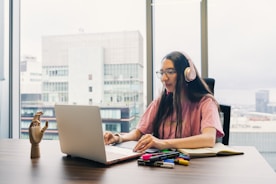 Young woman wearing headphones works on laptop