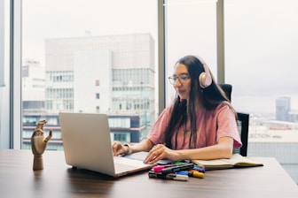 Young woman wearing headphones works on laptop