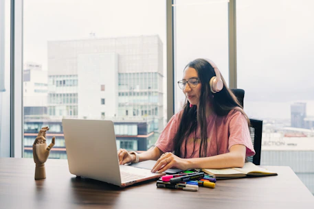 Young woman wearing headphones works on laptop