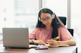 Young woman wearing headphones studying at desk