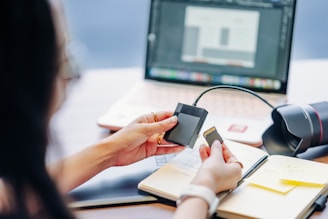 Person holding memory card near laptop and notebook.