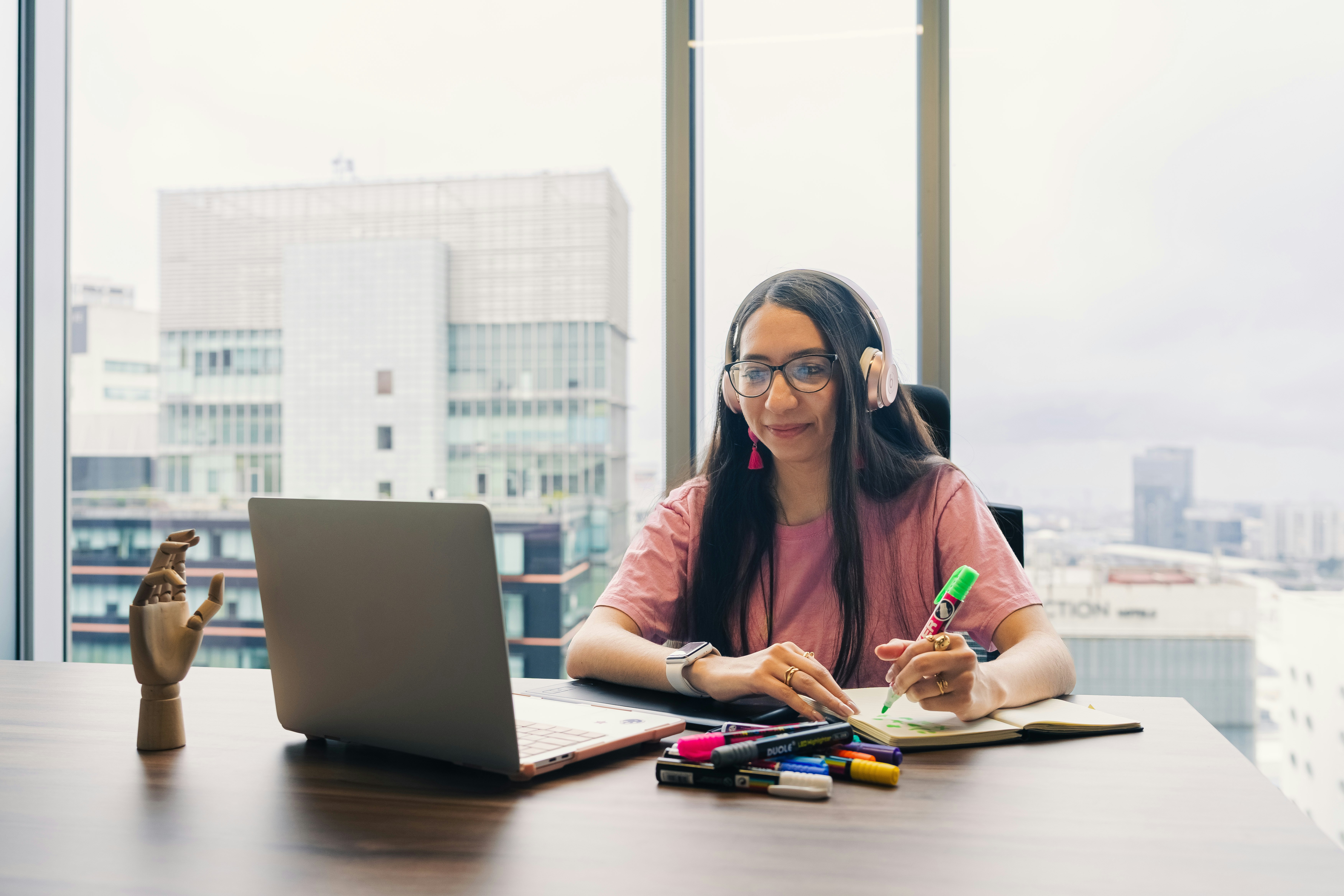 Woman wearing headphones works at desk with laptop.
